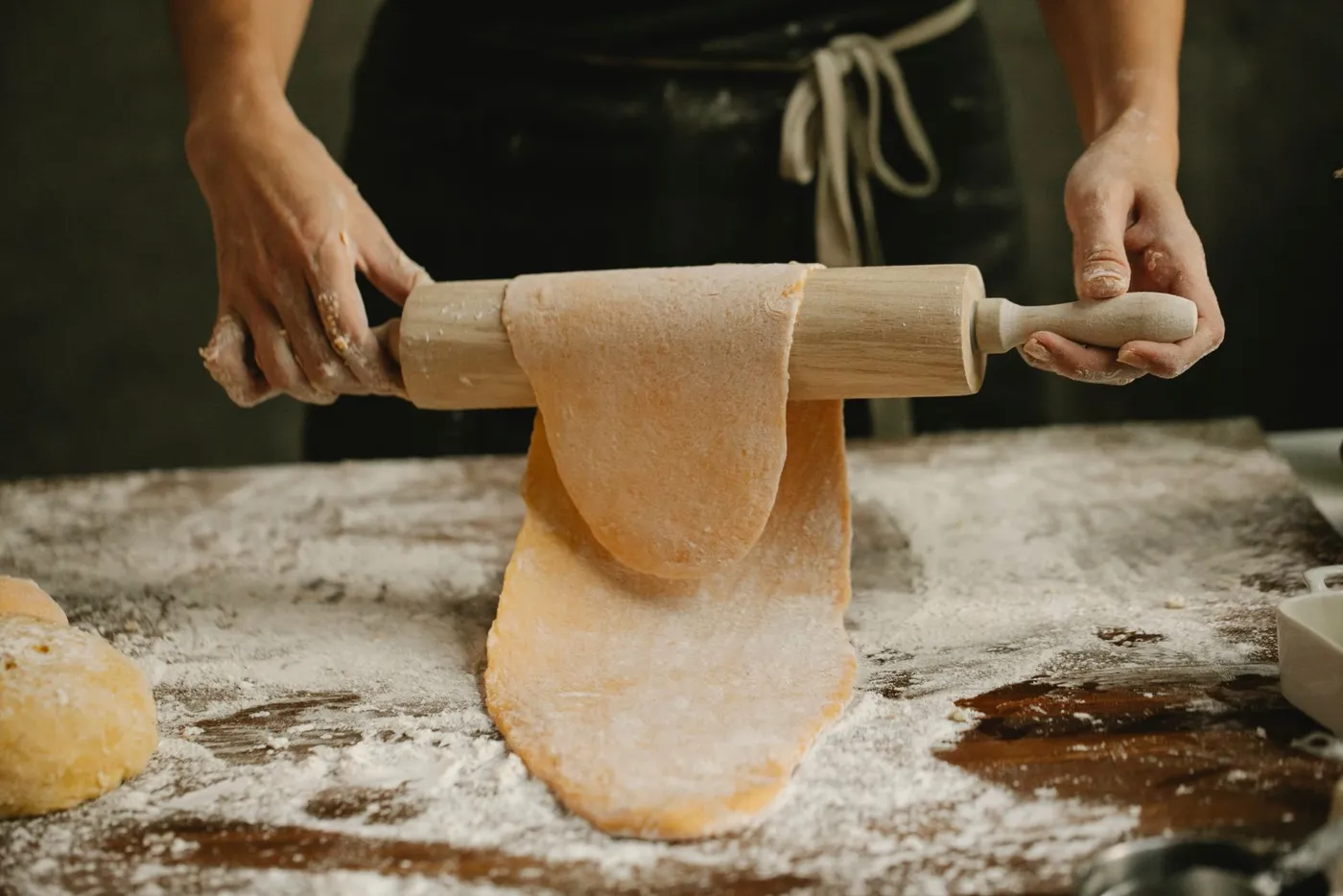 Hands rolling out fresh pasta dough