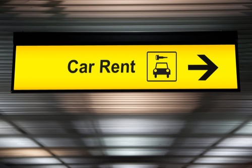 Schild Autovermietung mit Aufschrift "Car Rent", welches zur Autovermietung weist