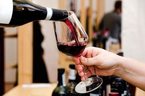 Rotwein wird in ein Glas eingeschenkt