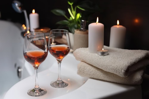 Wellnessszenerie mit Weingläsern und Kerzen am Rand eines Whirlpools